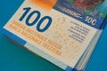 100 Swiss Francs CHF money bills bundle bright color closeup laying stacked up on blue background