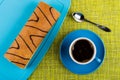 Swiss roll on cutting board, spoon, coffee in cup on mat. Top v