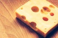 Swiss yellow cheese square chunks with holes on wood board. Fresh piece of cheese Royalty Free Stock Photo