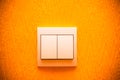 The switch on the wall. White classic light switch on a bright orange wall. Royalty Free Stock Photo