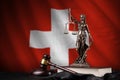 Switzerland flag with statue of lady justice, constitution and judge hammer on black drapery. Concept of judgement and Royalty Free Stock Photo