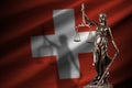 Switzerland flag with statue of lady justice and judicial scales in dark room. Concept of judgement and punishment Royalty Free Stock Photo