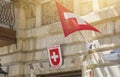 Switzerland national flags flying in the wind by a building in a city, square red flag with white cross Royalty Free Stock Photo