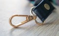 Swivel carabiner fastener with leather black bag strap on a wooden background. Metal carabiner with swivel clip or hook. Small