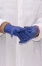 Swollen hands of a doctor in latex gloves. The doctor puts on sterile gloves against the background of a medical gown. Royalty Free Stock Photo
