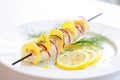 swordfish kebab with lemon slices on a white plate