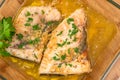 Swordfish stakes with lemon butter sauce and parsley. Two fish stakes close up in a glass bowl