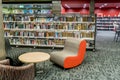 At the community public local library. Chairs waiting for readers and bookshelfs full of books.