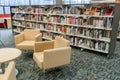 At the community public local library. Chairs waiting for readers and bookshelfs full of books.