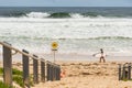 Danger sign at the entrance to the beach in Australia. Two surfers with surfboards walking by Royalty Free Stock Photo