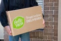 Delivery man holding Hello Fresh meal kits in a box near the front door Royalty Free Stock Photo