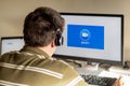 Man with headphones looking on the monitor with zoom cloud meetings logo