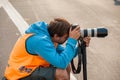 Official photographer crouching taking photos with a DSLR and zoom lens