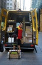 Branded yellow DHL courier service with employee dropping off a package delivery to a