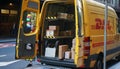 DHL express delivery car close up shot with open back doors, cardboard parcel boxes on shelves being visible