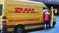 DHL yellow postal van with DHL employee making delivery