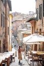 Sylish woman walks on narrow and cozy street in old town of Siena city
