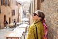 Sylish woman walks on narrow and cozy street in old town of Siena city