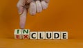 Symbol for a better inclusion. Male hand turns wooden cubes and changes word exclude to include. Beautiful orange background. Copy