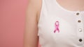 Symbol of breast cancer awareness month, pink october badge on the white shirt of unrecognizable woman Royalty Free Stock Photo