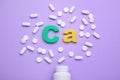 Symbol Ca Calcium, medical bottle and pills on violet background, top view Royalty Free Stock Photo