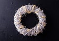 White rustic wreath with bright fairy ligts on black textured background.