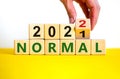 Symbol of covid-19 normal in 2022. Doctor turns a wooden cube and changes words `normal 2021` to `normal 2022`. Beautiful whit