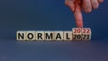 Symbol of covid-19 normal in 2022. Doctor turns wooden cubes and changes words `normal 2021` to `normal 2022`. Beautiful grey