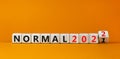 Symbol of covid-19 normal in 2022. Turned a wooden cube and changed words `normal 2021` to `normal 2022`. Beautiful orange