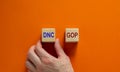 Symbol for the election in the United States. Hand picks a cube with the acronym DNC. Beautiful orange background, copy space.