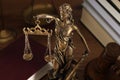 Symbol of fair treatment under law. Figure of Lady Justice, books and gavel on wooden table, closeup
