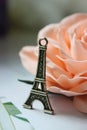 Miniature Eiffel tower in silver on the background of a blooming pink rose Royalty Free Stock Photo