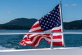 Symbol of freedom, American flag flying on the back of a boat cruising in the Salish Sea of the San Juan Islands, tree covered isl