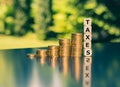 Symbol for increasing taxes. Dice form the word taxes next to increasing high stacks of coins Royalty Free Stock Photo