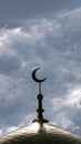 The symbol of Islam is a golden crescent moon on top of the mosque minaret on the blue evening of the morning sky with clouds. Ver Royalty Free Stock Photo