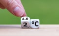 Symbol for limiting global warming. Hand turns a dice and changes the expression `2ÃÂ°C` to `1.5ÃÂ°C`, or vice versa.