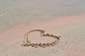 A symbol of love, the heart is painted on the yellow-pink sand on the beach. Royalty Free Stock Photo