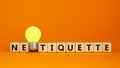 Symbol for netoquette time. Wooden cubes with word `netiquette`. Yellow light bulb. Beautiful orange background. Copy space.