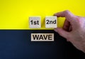 Symbol for a second wave of the corona virus. Hand holds cube with words `1st, 2nd, wave`. Copy space. Beautiful yellow and red Royalty Free Stock Photo