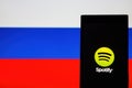Symbol of Spotify app on screen of mobile phone against background of Russian flag Royalty Free Stock Photo