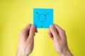 Symbol of transgender painted on a sticker in man hands on a yellow background