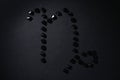 Symbol of the zodiac sign Capricorn made by black stones on a black background. Low dark key