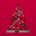 A symbolic Christmas tree made of construction tools on a red background.