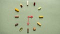 Symbolic clock with plasticine hands and a pill and vitamin dial.