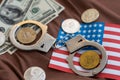 Symbolic coins of bitcoin and stack of bitcoin coins and metall handcuffs on banknotes of one hundred dollars. Exchange