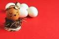 Self-centered light brown egg with satin flower in bed tones in nest of birch twigs and white eggs on bright red background. Minim