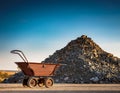 A symbolic image of an empty mining cart beside a heap of unmined rock, highlighting the potential of untouched natural resources
