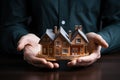 Symbolic image Hands covering a small house, signifying home insurance