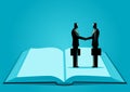 Symbolic image of two businessmen shaking hands while standing on the same page of an open book