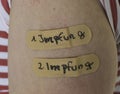 Plasters on Arm Skin with Words First and Second Vaccination german \